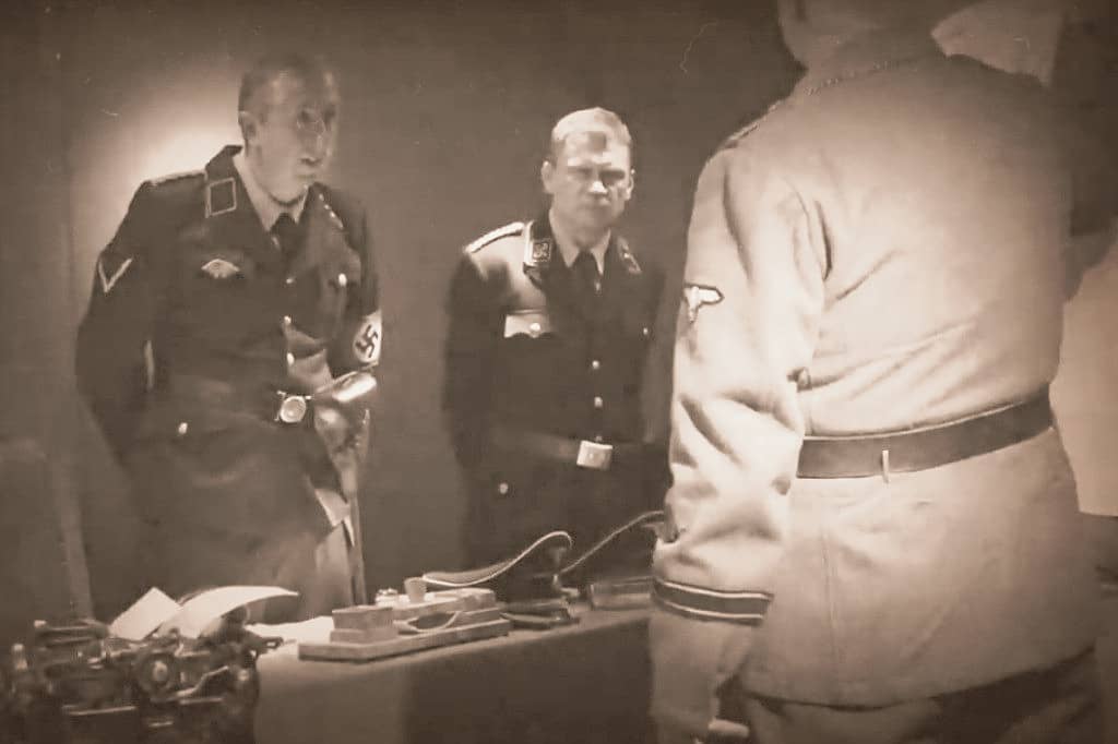 Zdjęcie przedstawia stojące osoby w niemickich mundurach z czasów II wojny